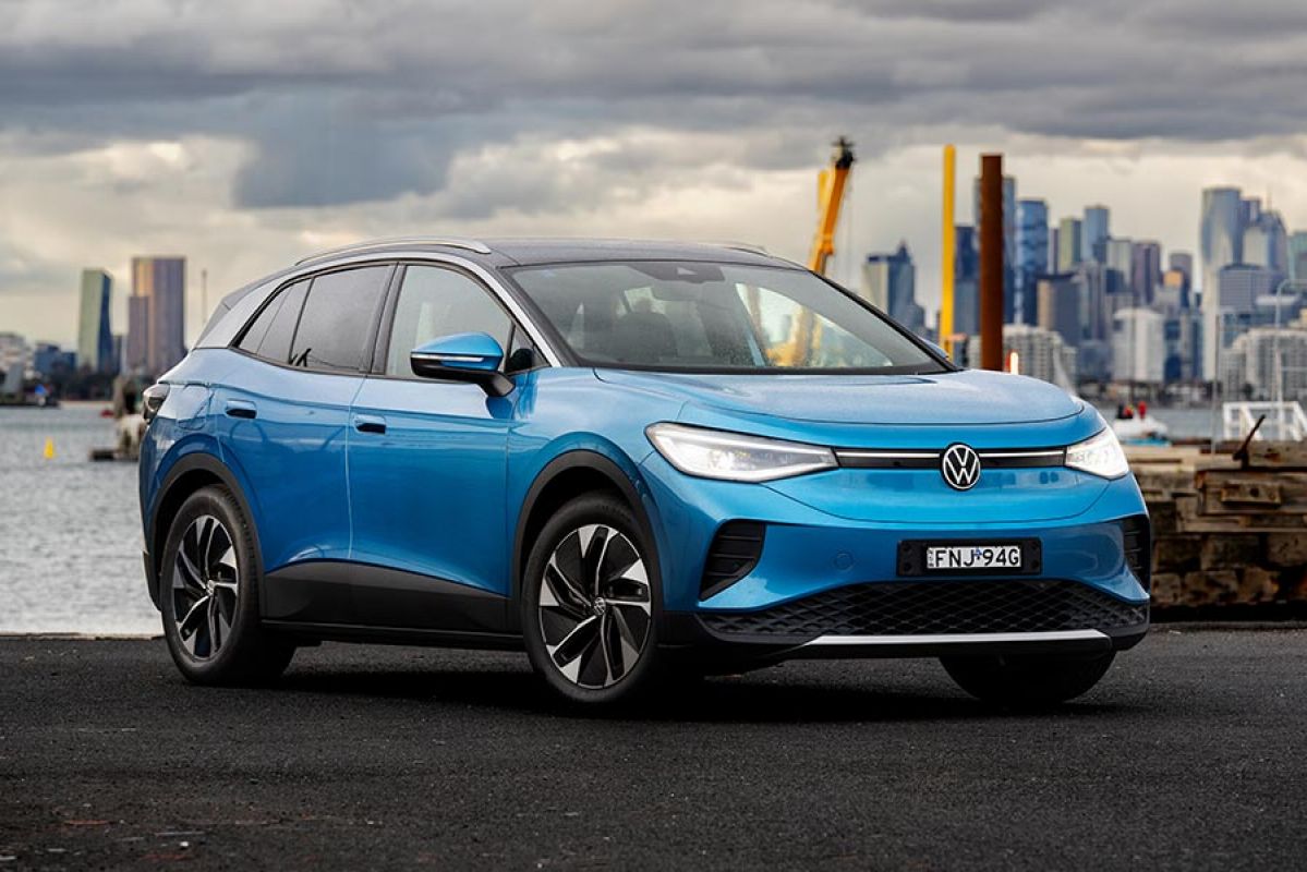 Blue Volkswagen ID.4 electric SUV on docks at Williamstown with Port Phillip Bay and city skyline behind.