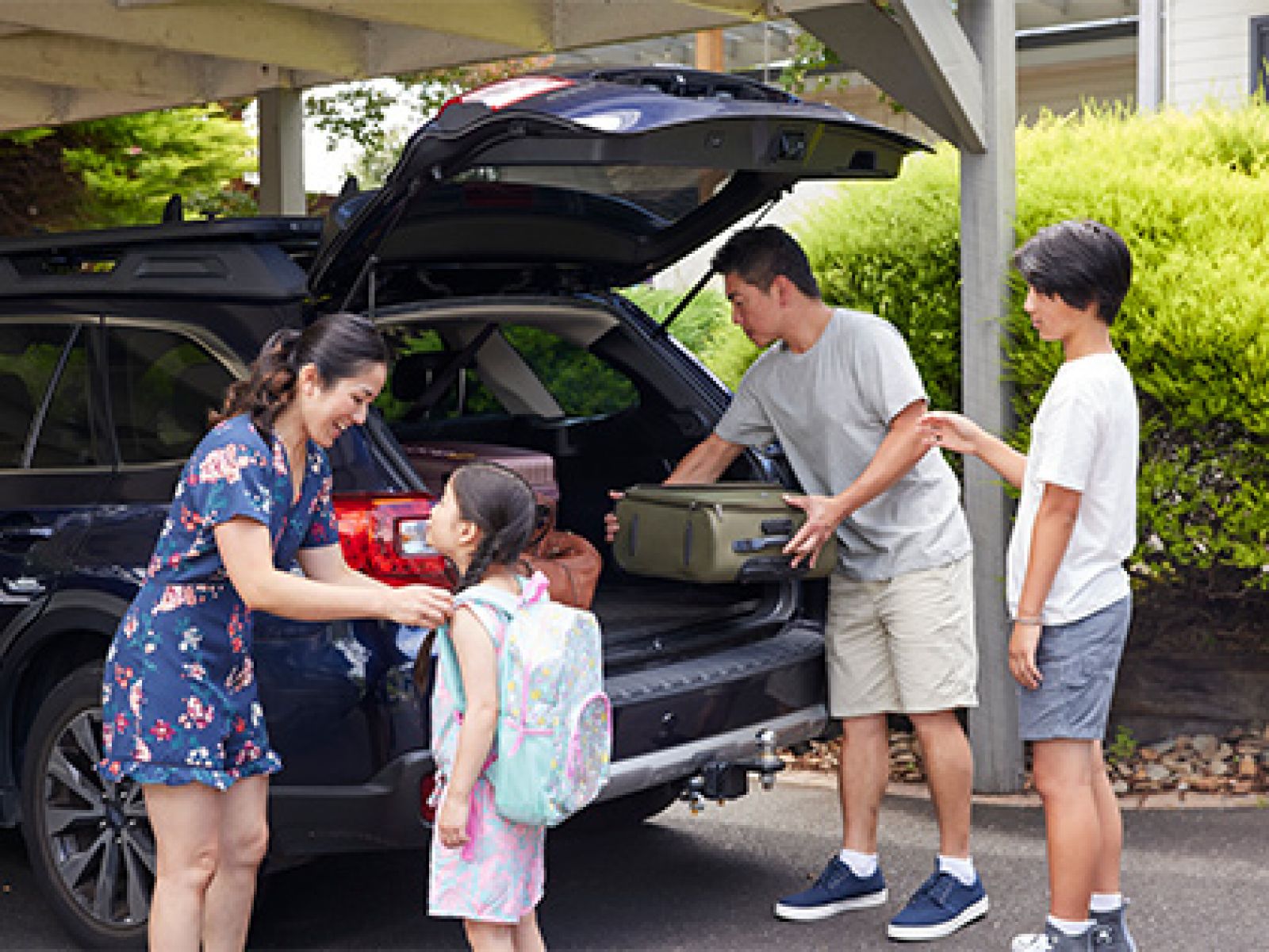 Family putting their suitcases in their car boot, in preparation for a holiday..