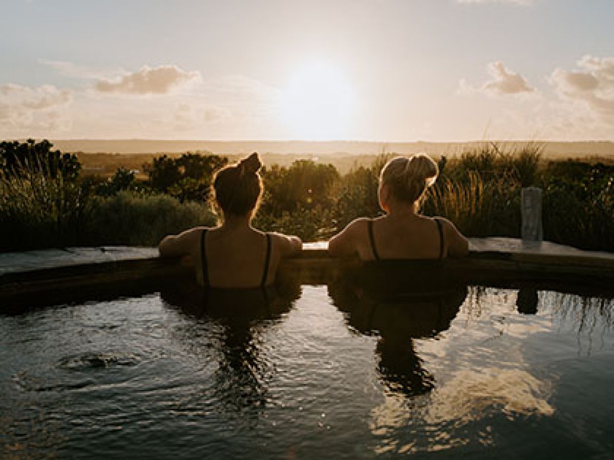 Two women looking over the edge of an outdoor bath at the peninsula landscape.