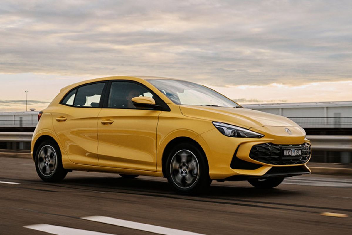 Yellow MG3 hybrid hatchback driving on multi-lane overpass with bright sky in background