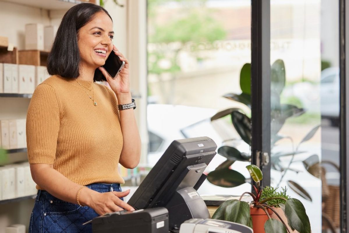 retail worker talking on phone while at till