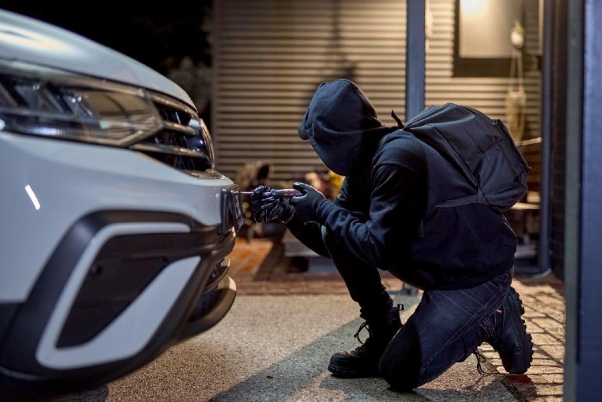thief stealing a car's number plates