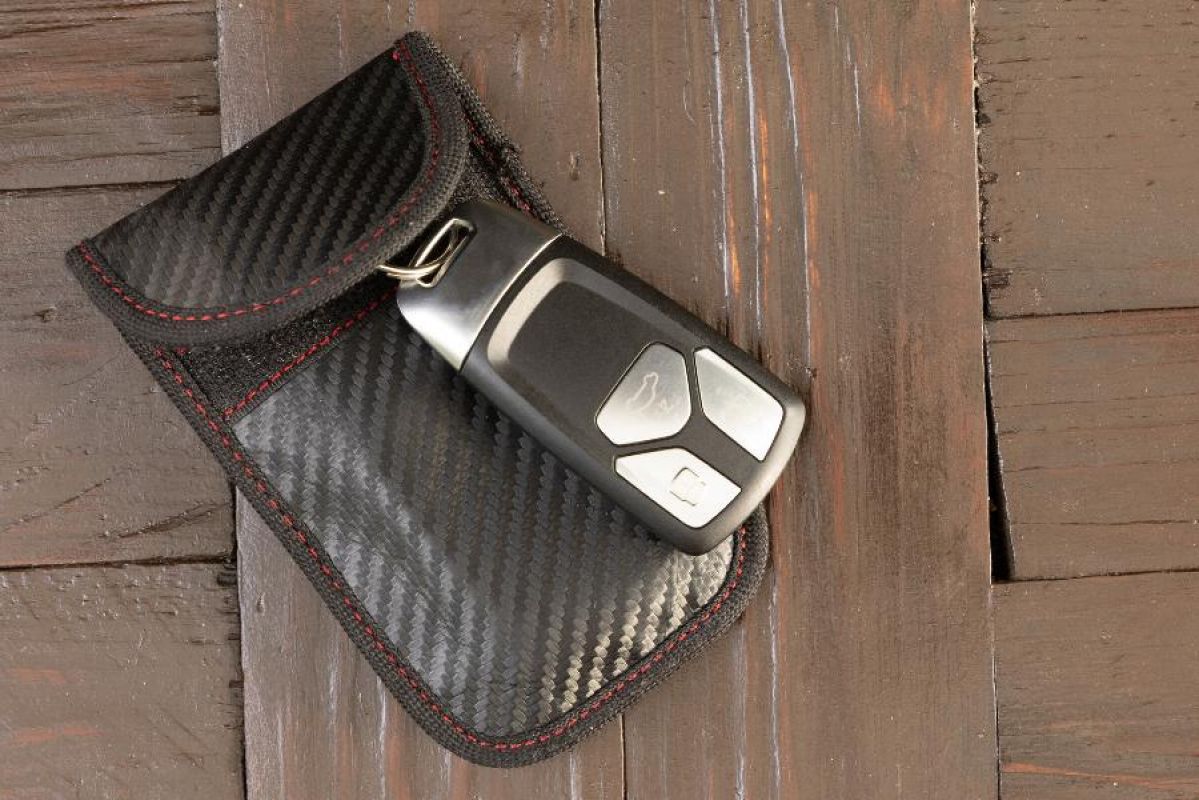 A keyless car fob sitting on top of a black Faraday pouch