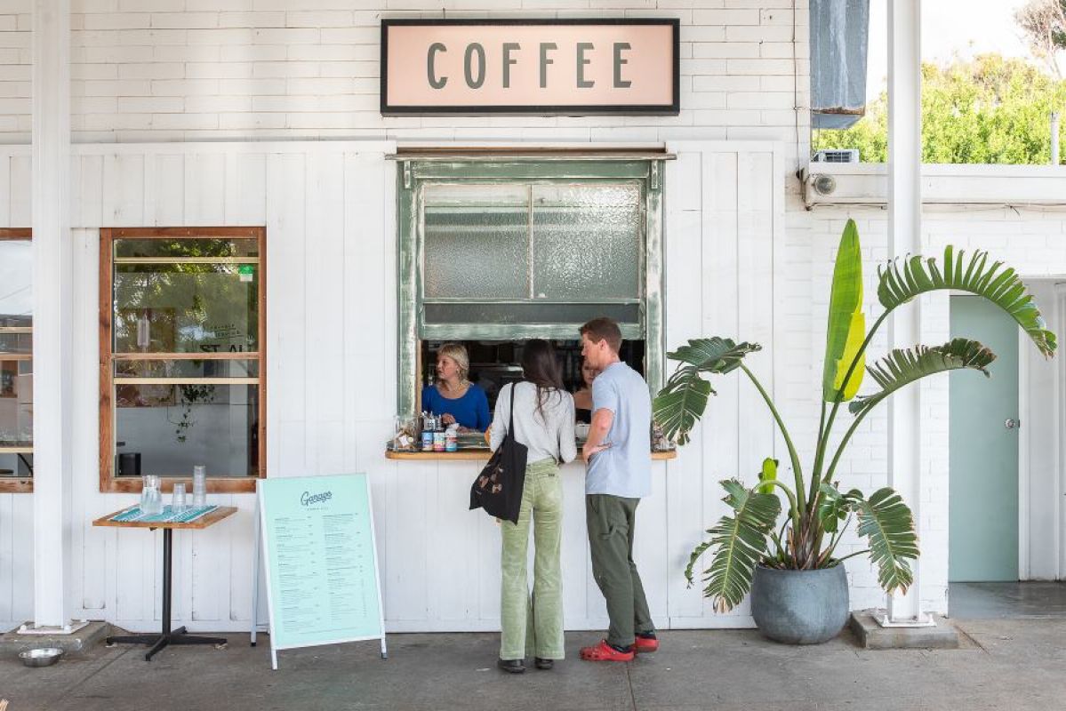 man and woman ordering coffee from whitewashed building