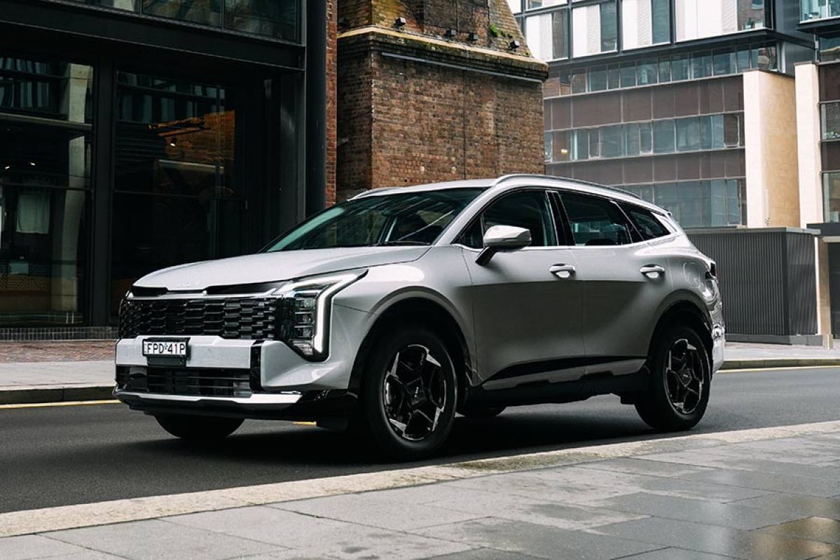 White Kia Sportage SX Hybrid SUV parked on street in urban industrial area