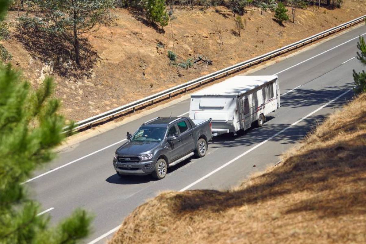 black trayback towing white caravan on road
