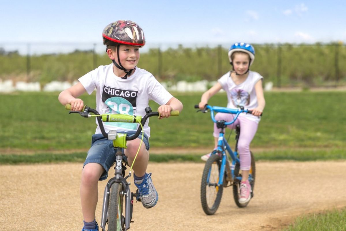 two young children riding bikes with helmets on