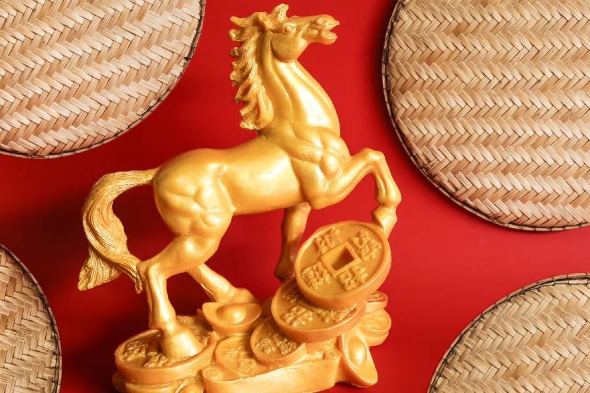gold horse statue with traditional Chinese coins on a red background