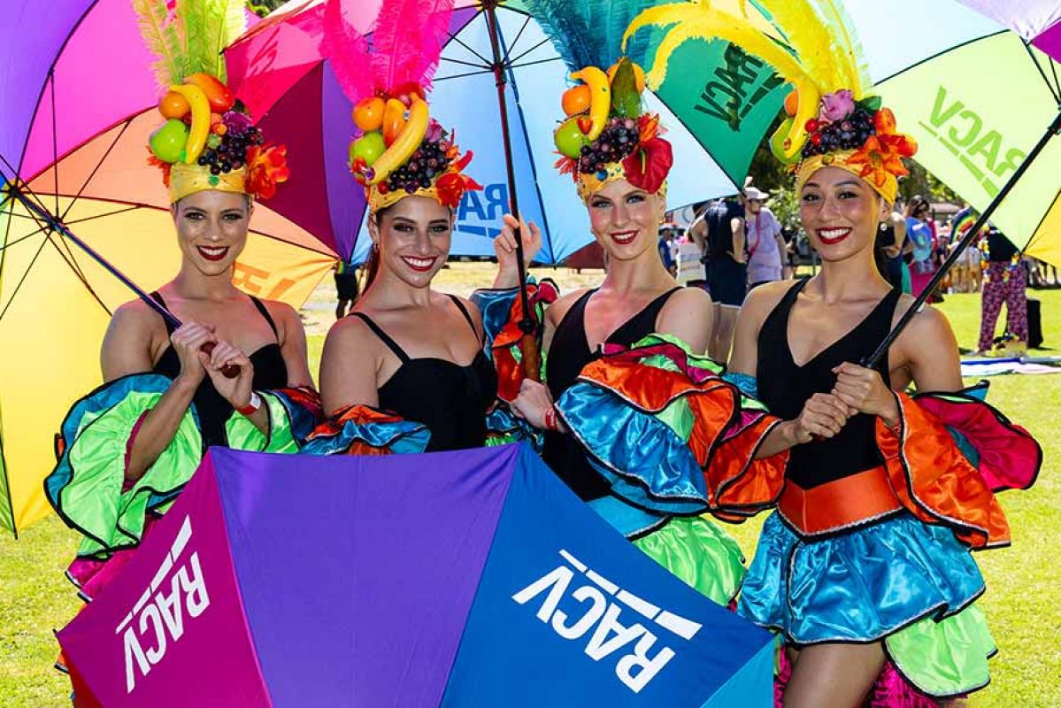 four women dressed up with rainbow umbrellas sporting the RACV logo