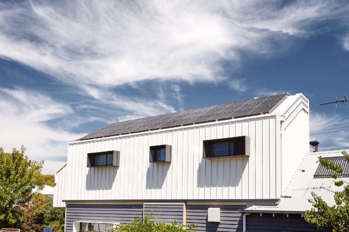 A large number of solar panels installed on a house roof under a lightly cloudy, wintery sky