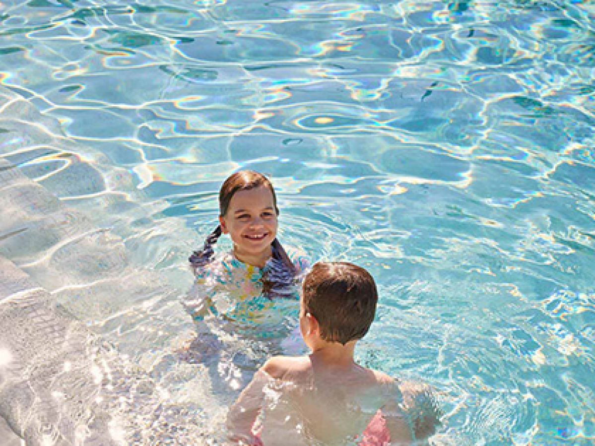 Two children swimming in outdoor pool at RACV Noosa Resort.