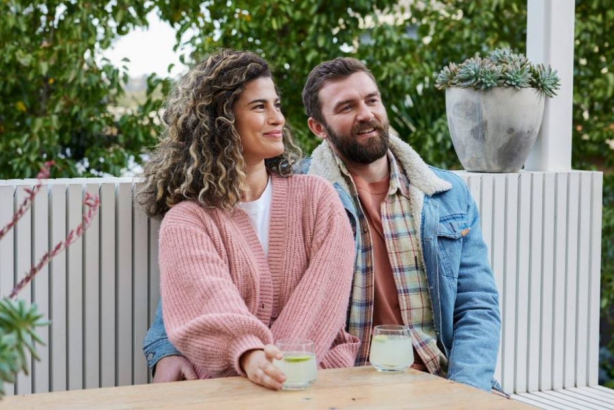 A couple sitting together outside with a drink each