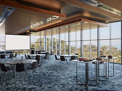 Cape Paterson room at RACV Inverloch Resort, set up cabaret style, with catering on a table and a screen coming down from the ceiling.