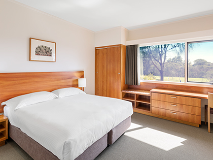 Premium villa at RACV Inverloch Resort, featuring a large bed, wooden cabinets and desk.