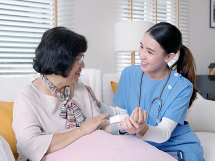 Nurse wearing scrubs talking to an elderly woman.