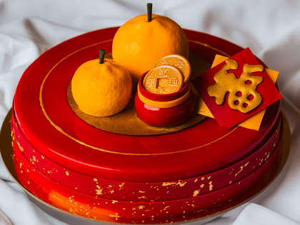 A red and orange cake decorated with oranges and coings for Lunar New Year