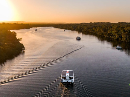 Boat going down a river at sunset in Noosa
