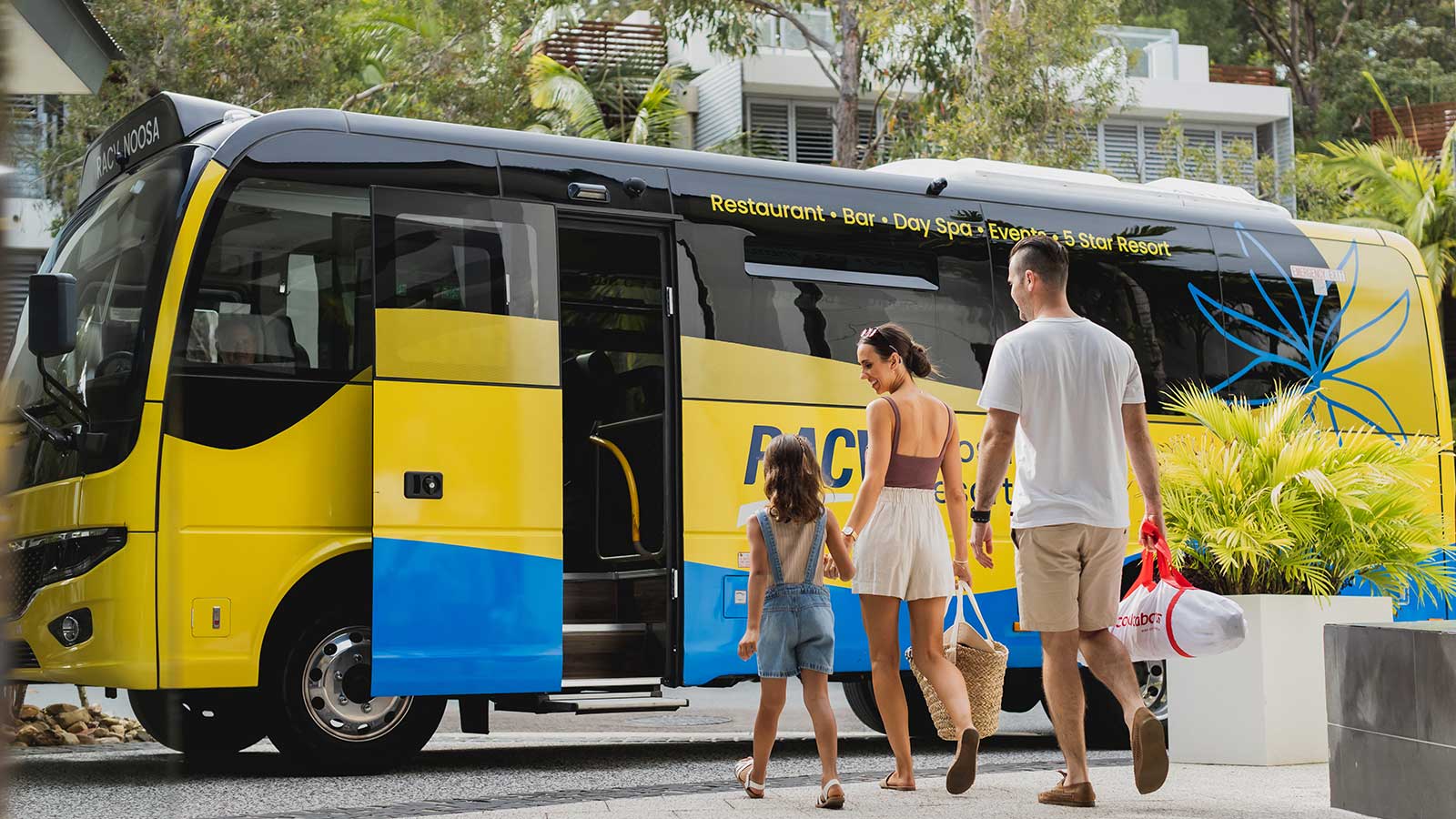 Parents and child getting on RACV Noosa Resort's yellow and blue shuttle bus.