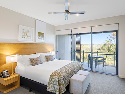 One bedroom suite at RACV Noosa Resort, featuring a king bed and a balcony with a table.