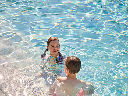 Two children swimming in outdoor pool at RACV Noosa Resort.