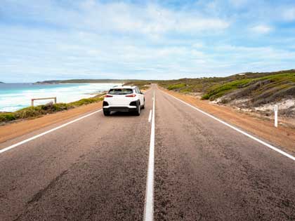A white car driving on a costal road