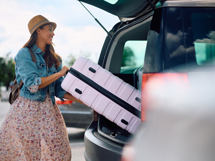 Woman putting her suitcase into the boot of her car to go to the airport