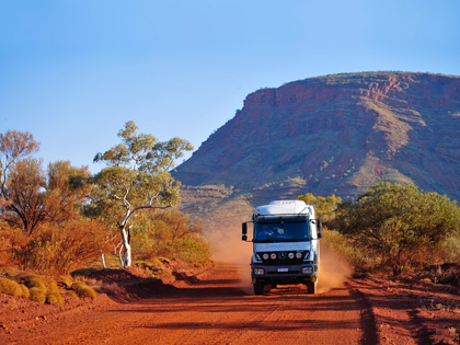 A bus driving through the red dirt in Pilbarra region.