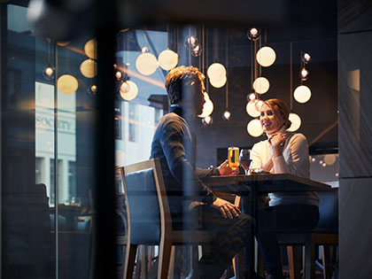 Couple seated at RACV Hobart Apartment Hotel restaurant, shown through window.