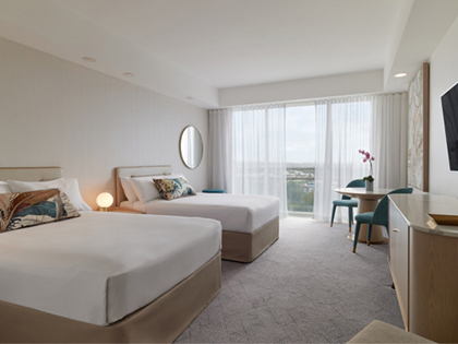 Executive room at RACV Royal Pines, featuring two double beds, a desk and a television.