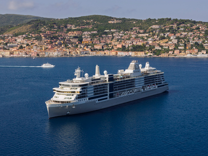 A cruise ship in the waters with the Itallian coast in the background. 