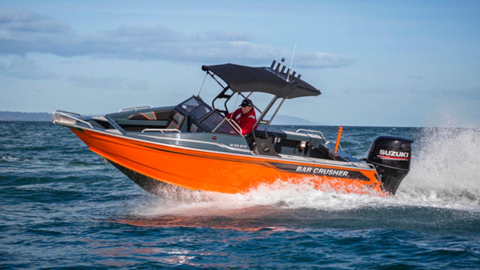 A man steering an orange speed boat in the ocean.