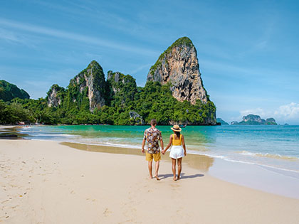 Railay Beach Krabi Thailand, the tropical beach of Railay Krabi, a couple of men and woman on the beach, Panoramic view of idyllic Railay Beach in Thailand with a traditional long boat. 