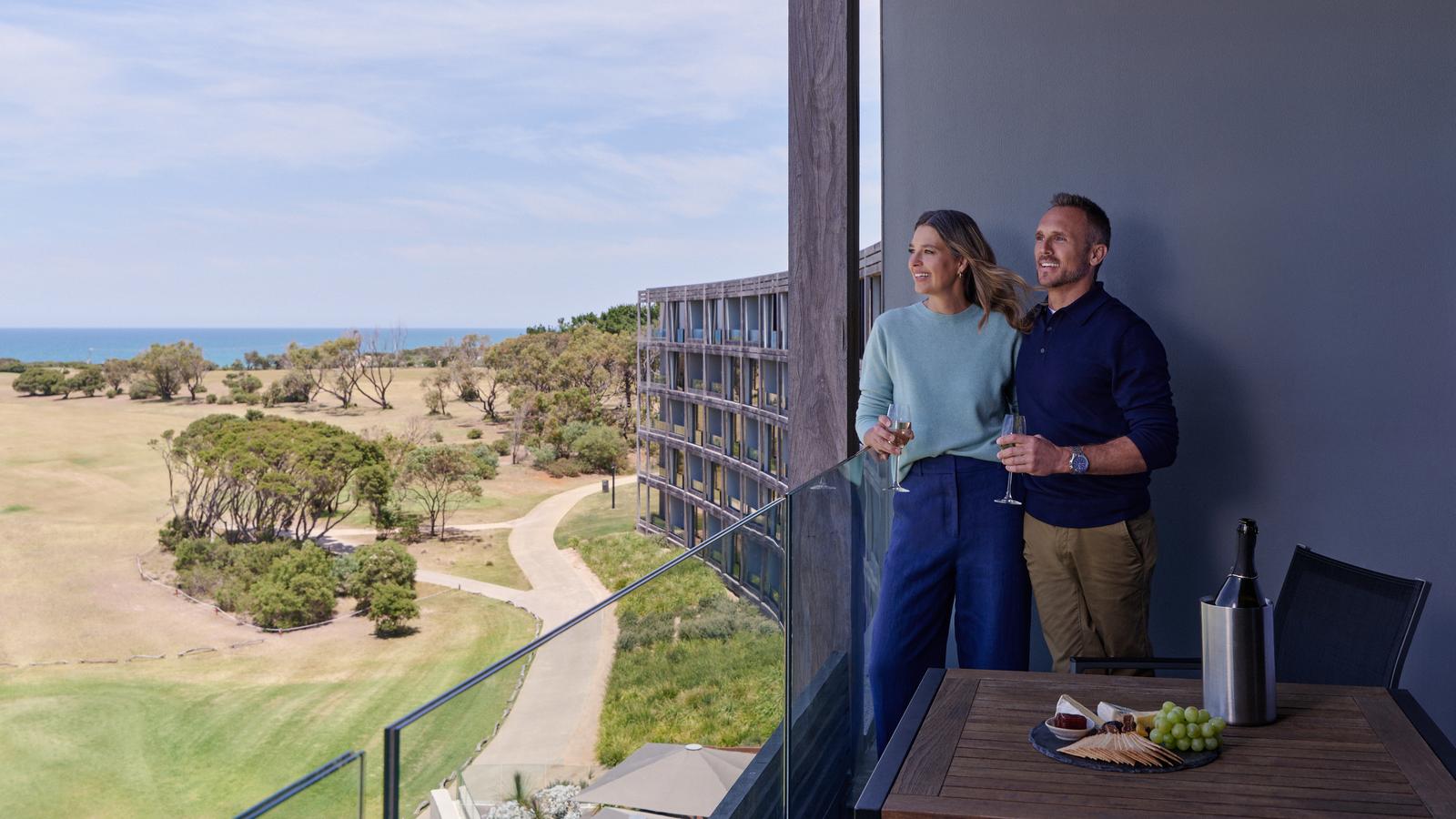 A couple enjoying the view on the balcony of the premium ocean view room at RACV Torquay Resort.