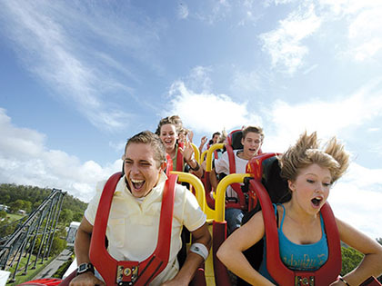 People riding a roller coaster at one of the Village Roadshow theme parks.