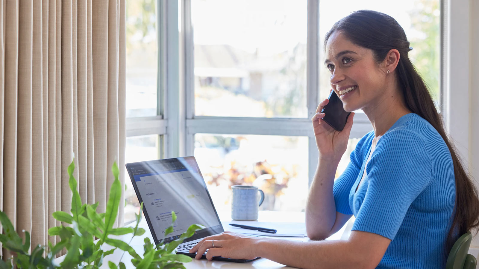 Woman talking on the phone while sitting in front of her laptop