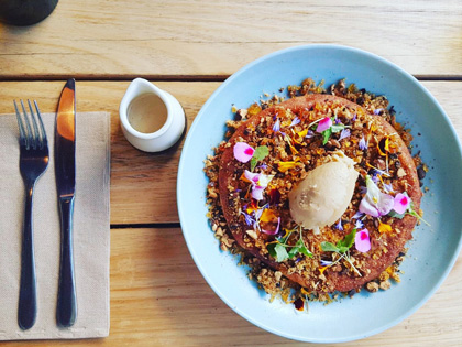 A Vibrant colorful meal placed on a table with a side of gravy and cutlery. 